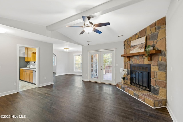 unfurnished living room with french doors, a stone fireplace, dark hardwood / wood-style floors, lofted ceiling with beams, and ceiling fan