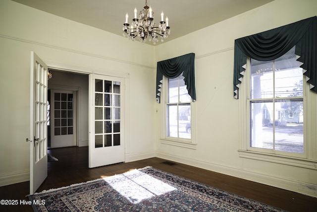 interior space with plenty of natural light, a chandelier, dark hardwood / wood-style flooring, and french doors