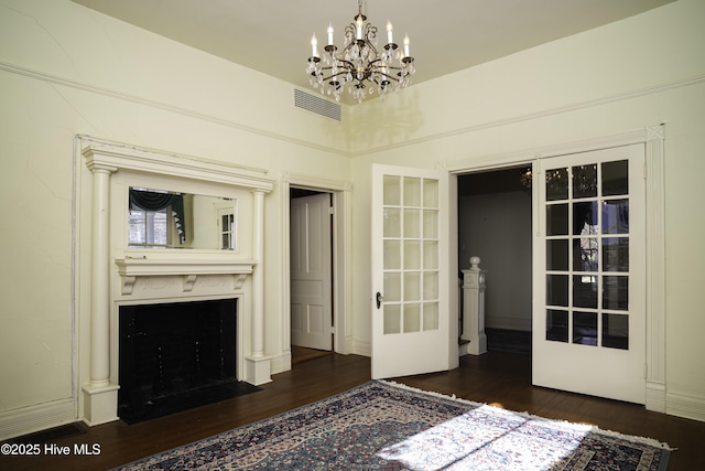 unfurnished bedroom featuring dark wood-type flooring, french doors, and a notable chandelier