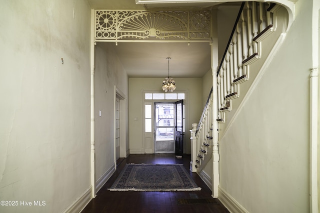 doorway to outside with a high ceiling, dark wood-type flooring, and a notable chandelier