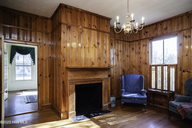 unfurnished living room with wood walls, a chandelier, and hardwood / wood-style floors