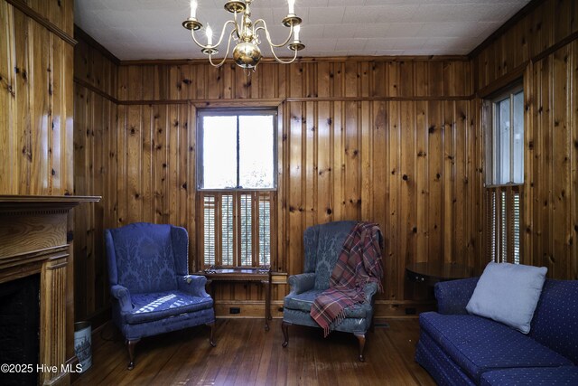 living area featuring hardwood / wood-style floors, a chandelier, and wooden walls