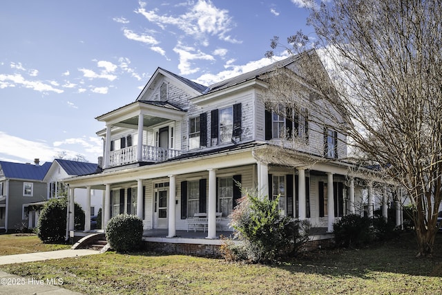 view of front of property featuring a front yard, a porch, and a balcony