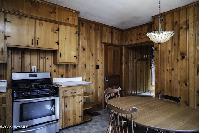 kitchen featuring stainless steel range with gas cooktop, pendant lighting, and wood walls