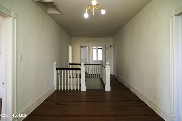 hallway with dark hardwood / wood-style floors and a chandelier