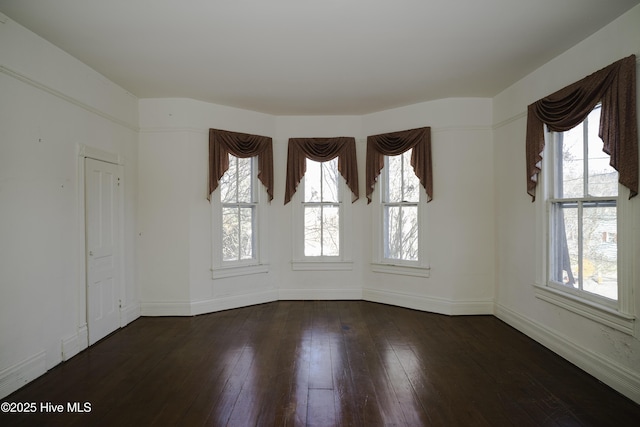 empty room featuring dark hardwood / wood-style flooring and plenty of natural light