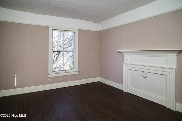 spare room featuring a textured ceiling and dark hardwood / wood-style flooring