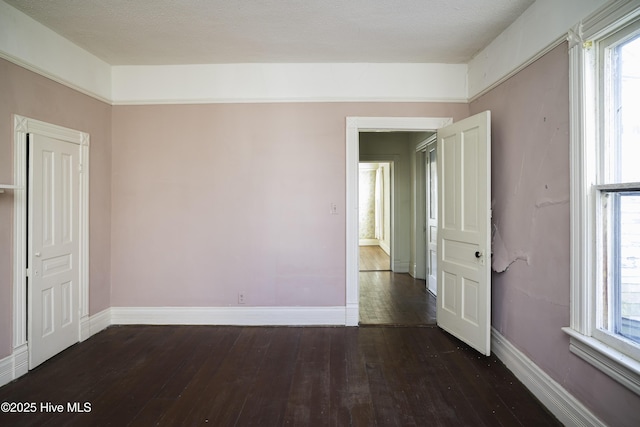 spare room with dark hardwood / wood-style flooring and a wealth of natural light