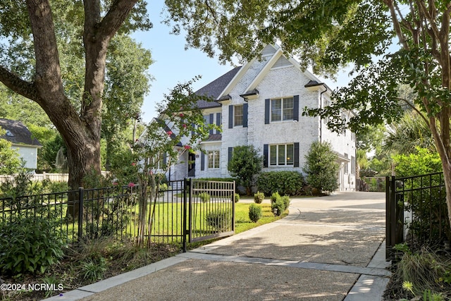 view of front of property with concrete driveway, brick siding, and fence