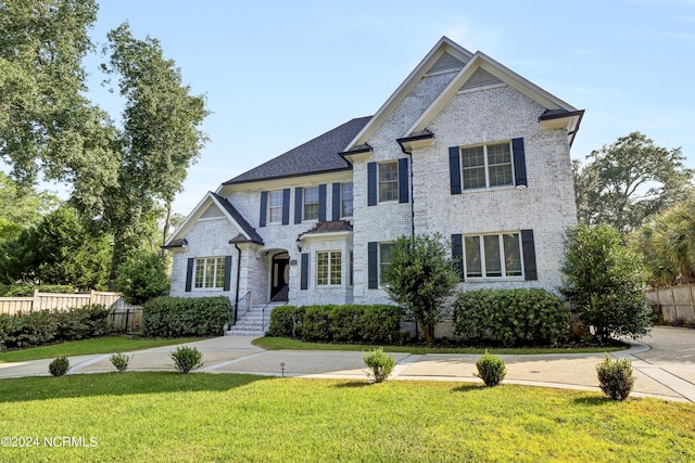 view of front of property with fence, a front lawn, and brick siding