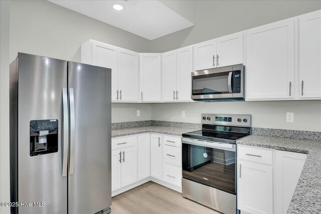211 Lincoln Place Cir, Leland, NC 28451 - kitchen featuring appliances with stainless steel finishes, white cabinetry, light wood finished floors, light stone countertops, and recessed lighting