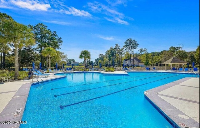 community pool with a gazebo and a patio