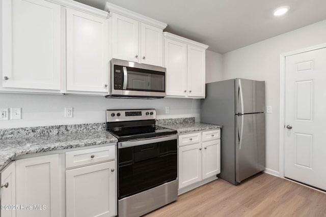 kitchen featuring stainless steel appliances, light hardwood / wood-style floors, white cabinets, and light stone counters