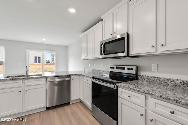 kitchen with sink, white cabinetry, light hardwood / wood-style flooring, light stone countertops, and appliances with stainless steel finishes