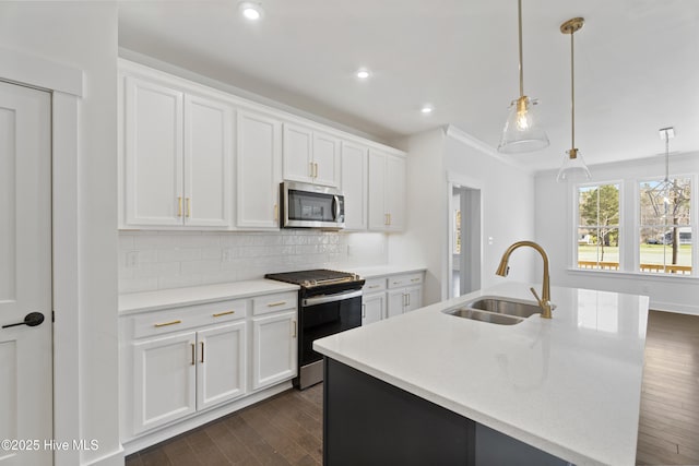 kitchen with appliances with stainless steel finishes, a center island with sink, hanging light fixtures, and sink