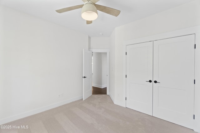 unfurnished bedroom featuring ceiling fan, a closet, and light carpet