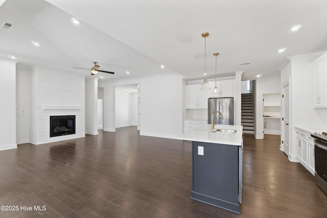 kitchen featuring white cabinetry, appliances with stainless steel finishes, a kitchen island with sink, hanging light fixtures, and sink