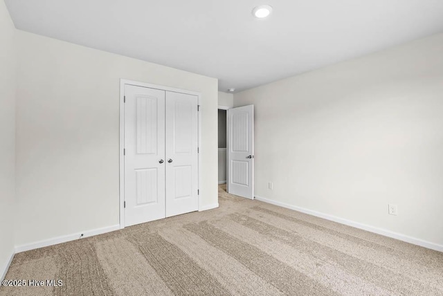 unfurnished bedroom featuring light carpet and a closet