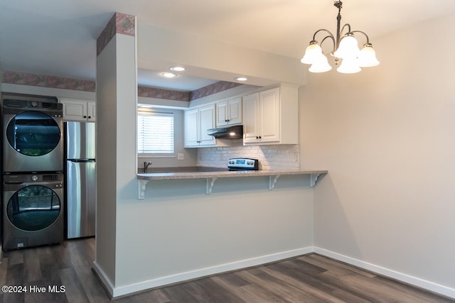 kitchen with pendant lighting, white cabinets, kitchen peninsula, stacked washing maching and dryer, and stainless steel refrigerator