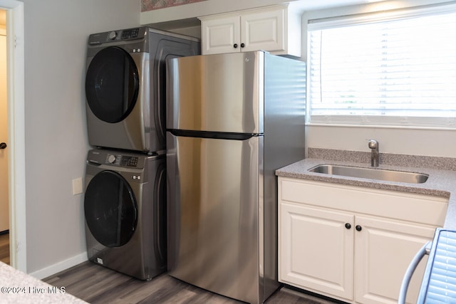 clothes washing area featuring sink, stacked washer / drying machine, and dark hardwood / wood-style floors