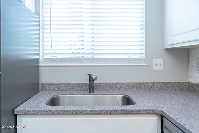 kitchen with sink, stainless steel fridge, and white cabinets