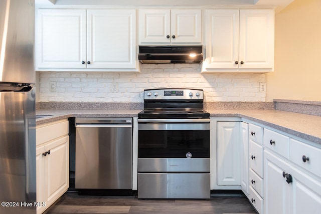 kitchen with dark wood-type flooring, stainless steel appliances, white cabinetry, and tasteful backsplash