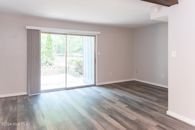 spare room with dark hardwood / wood-style floors and beamed ceiling