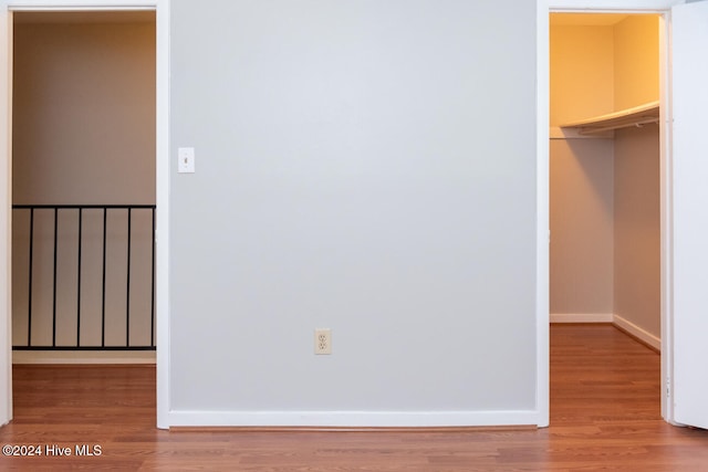 unfurnished bedroom with a spacious closet, hardwood / wood-style flooring, and a closet