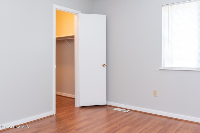 unfurnished bedroom featuring a closet, a spacious closet, and wood-type flooring