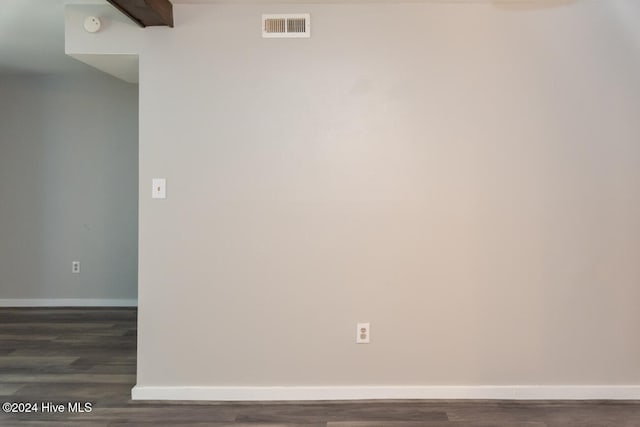 spare room featuring dark wood-type flooring and beamed ceiling