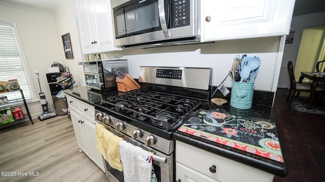 kitchen featuring light hardwood / wood-style floors, white cabinets, appliances with stainless steel finishes, and ornamental molding