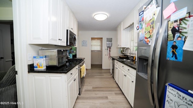 kitchen with light hardwood / wood-style floors, sink, white cabinetry, appliances with stainless steel finishes, and dark stone counters