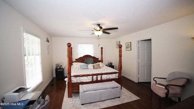 bedroom featuring ceiling fan, dark hardwood / wood-style floors, and multiple windows