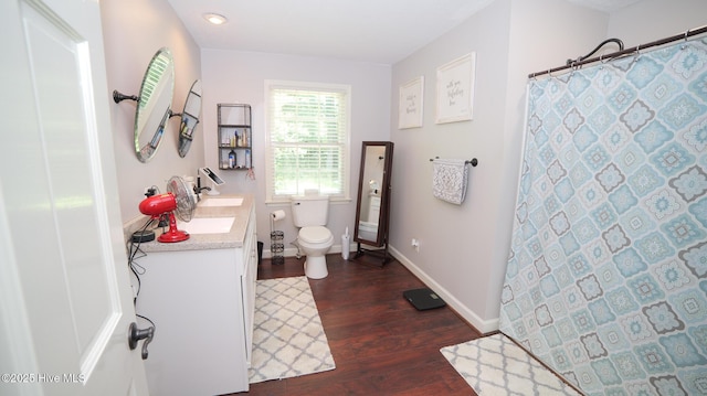 bathroom featuring hardwood / wood-style flooring, toilet, vanity, and walk in shower