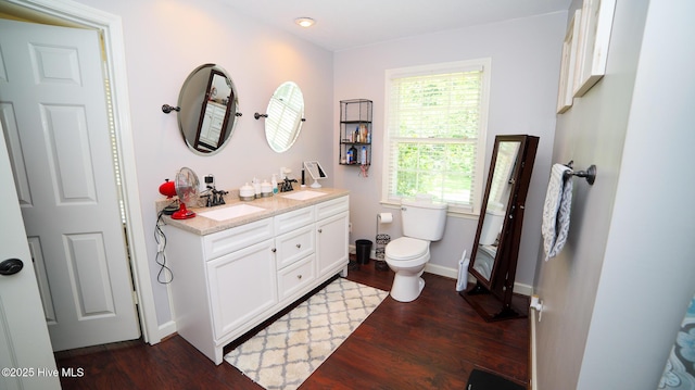 bathroom with toilet, a wealth of natural light, hardwood / wood-style flooring, and vanity