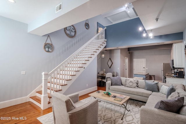 living room with light wood-type flooring and a towering ceiling