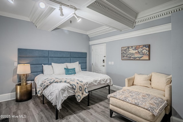 bedroom featuring rail lighting, ornamental molding, and hardwood / wood-style floors