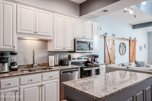 kitchen featuring white cabinets, appliances with stainless steel finishes, and a barn door