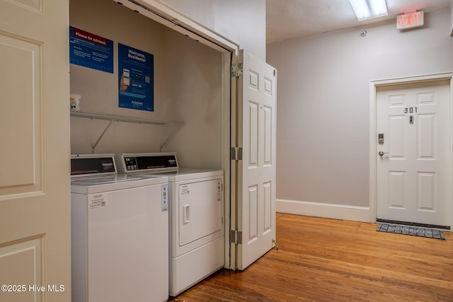 clothes washing area featuring washing machine and clothes dryer and light hardwood / wood-style flooring