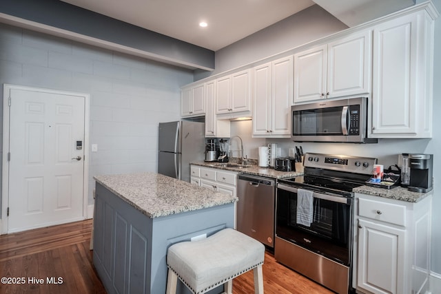 kitchen with a kitchen breakfast bar, stainless steel appliances, white cabinets, and a center island