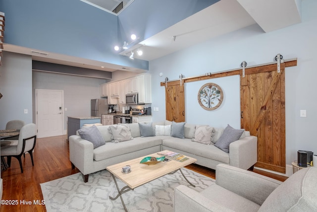 living room with a high ceiling, wood-type flooring, and a barn door