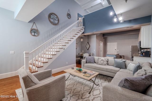 living room with light hardwood / wood-style floors and a towering ceiling