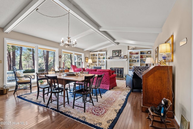 dining room with hardwood / wood-style floors, a brick fireplace, a notable chandelier, a textured ceiling, and lofted ceiling with beams