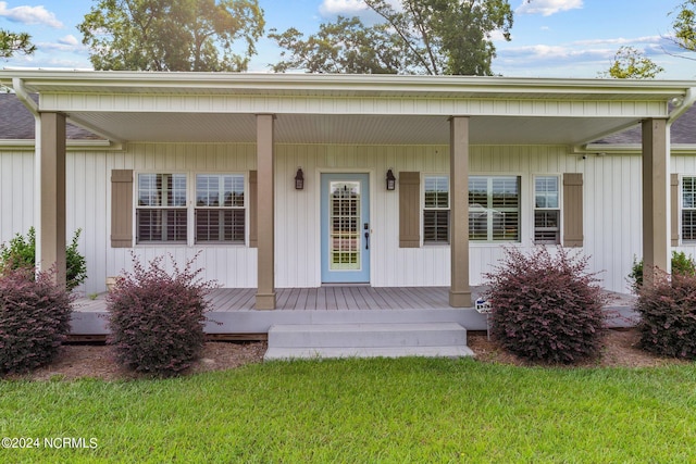 view of exterior entry with a yard and a porch