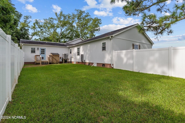 back of house with a deck and a yard