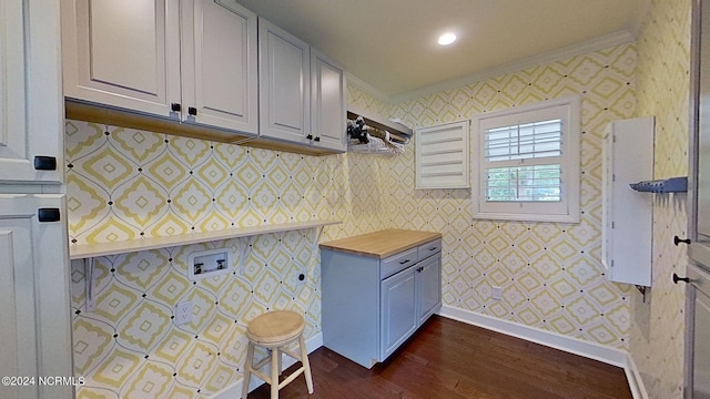 kitchen with dark wood-type flooring, crown molding, white cabinets, and butcher block counters