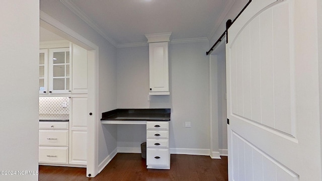 unfurnished office featuring a barn door, dark hardwood / wood-style floors, and crown molding