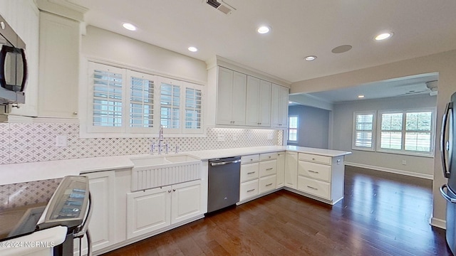 kitchen with appliances with stainless steel finishes, white cabinets, kitchen peninsula, and sink