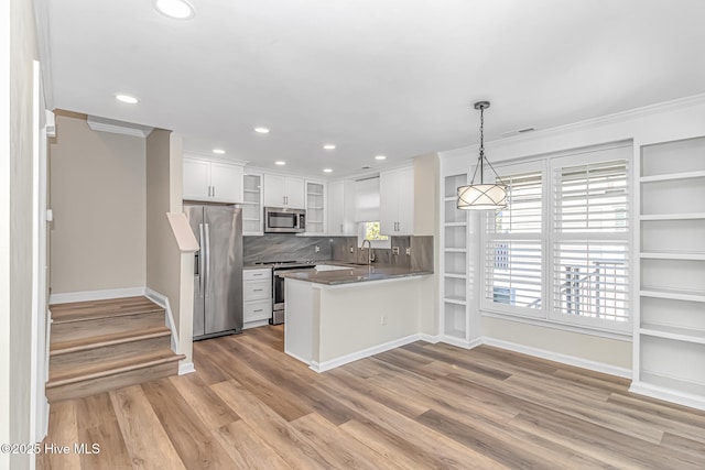 kitchen featuring white cabinets, appliances with stainless steel finishes, decorative light fixtures, sink, and kitchen peninsula