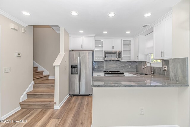 kitchen with kitchen peninsula, tasteful backsplash, pendant lighting, white cabinets, and sink
